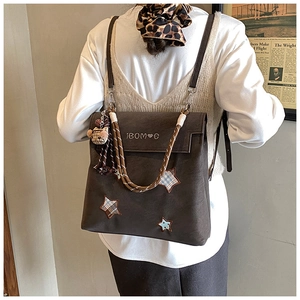 Detailed back view of vintage brown backpack with star patch and plaid bear keychain