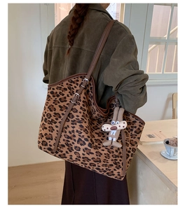Détail du sac cabas léopard avec lanières en cuir marron et breloque lapin en peluche