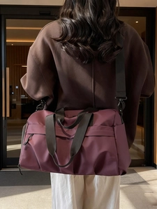 Große weinrote Reisetasche aus Canvas mit abnehmbarem Schultergurt am Modell gezeigt