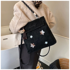 Detail of black frosted crossbody bag with star patches and woven shoulder strap