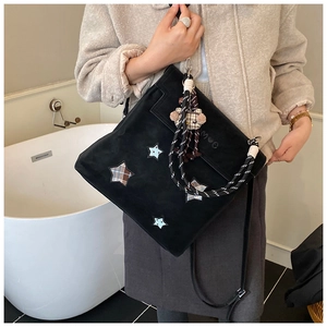 Detail of suede tote bag featuring star patches, love embossing and woven rope handles