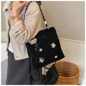 Detail view of black velvet backpack with star patch and braided rope shoulder straps