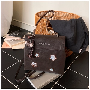 Detail of a brown frosted backpack featuring a star patch and woven rope handle