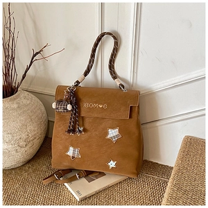 Close-up of brown matte leather backpack with star embroidery and teddy bear charm