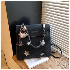 Detail of matte black tote bag featuring plaid star patches and a cute cat plush charm
