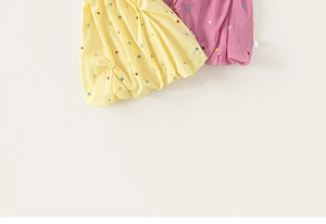 Close-up of summer cotton linen dresses with floral embroidery in yellow and pink