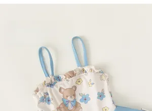 Détail du maillot de bain fille avec motifs d'oursons et fleurs bleues délicates sur blanc