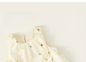 Detail of floral embroidery on cream sleeveless dress with pleated round neckline