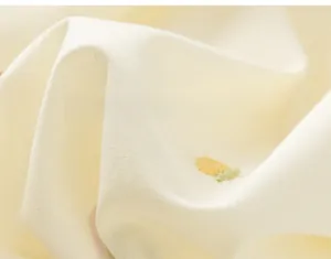 Close-up of soft yellow cotton fabric with delicate twill weave and small floral embroidery