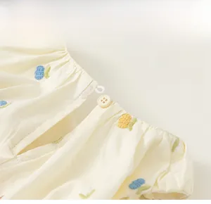 Close-up of baby girl beige dress with floral embroidery and back button detail