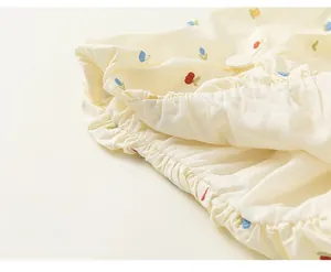 Detailed macro view of the colorful floral embroidery and elastic waistband on the girls dress