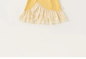 Dettaglio dell'abito giallo a trapezio da bambina con balze color crema a tre strati e trama fine