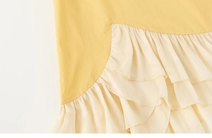 Dettaglio dell'abito in cotone con tessuto giallo e balze color crema stratificate