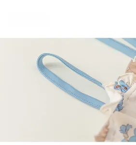 Détail des fines bretelles bleues et du tissu à volants fleuris sur un maillot fille