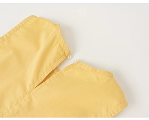 Dettaglio dello scollo dell'abito giallo zenzero con chiusura a bottone e cuciture