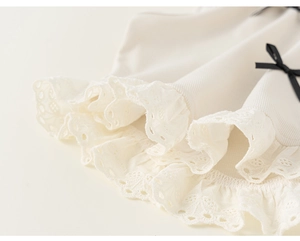 Dettaglio top in maglia a coste per bambina con bordo in pizzo e fiocco di raso nero