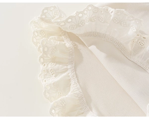 Dettaglio del tessuto a costine color crema con bordo in pizzo bianco traforato rifinito