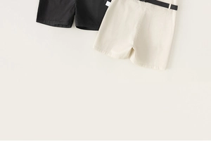 Close-up of boys summer twill cotton shorts in black and beige with a decorative belt