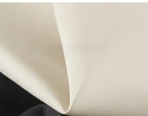 Close-up of premium cream-colored cotton fabric showing the fine woven texture of the romper