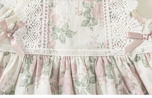 Close-up of floral girls dress with pink satin bows and delicate white lace detailing