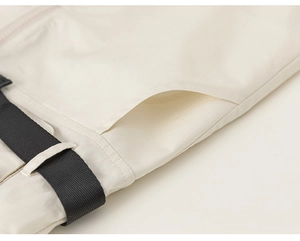 Detail of cargo romper side pocket with black nylon belt on beige cotton fabric