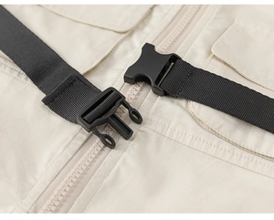 Detail of baby boy beige utility romper showing quick-release buckle and smooth zipper