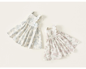 Flat lay of floral girls' sundresses with lace straps and side bow details in cotton