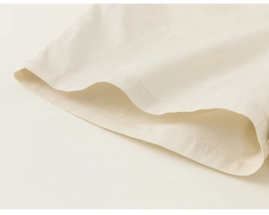 Close-up of cream white cotton linen romper showing clean double-stitched hem texture