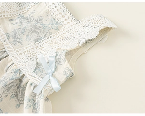 Close-up of floral girls dress featuring white lace trim and a blue silk bow detail