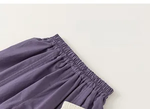 Detail view of the elastic waistband and pleated texture on deep purple children's trousers