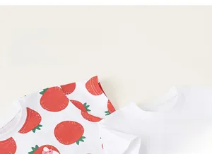 Dettaglio di una t-shirt in cotone con stampe di fragole e gatti carini per bambini