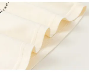 Detail shot of cream cotton t-shirt featuring precision double-stitch sewing and soft fabric