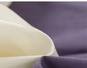 Detail shot of soft twill cotton fabric texture showing layers of cream and purple fabric