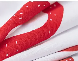 Dettaglio macro del tessuto in cotone con stampa di fragole rosse e pois bianchi