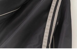 Detailed macro view of the smooth black fabric and grey side stripes on the boy's jacket