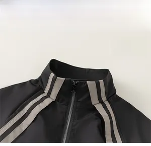 Detail of the stand-up collar with grey stripes and metal zipper on black sports jacket