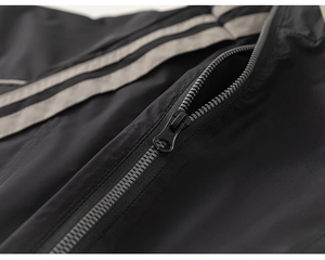 Detailed close-up of smooth black sports jacket zipper with gray decorative side stripes