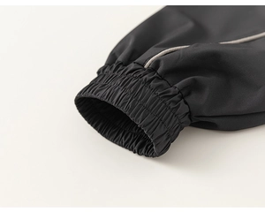 Detail of black windbreaker elastic cuff featuring silver reflective piping for safety