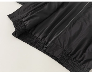 Detailed macro view of the elastic hem and zipper on this black boys windbreaker jacket