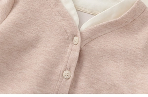 Detailed macro view of pink knit cardigan fabric with white buttons and soft texture