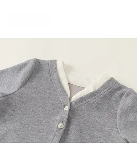 Detail shot of a grey knit cardigan featuring a faux layered white collar and buttons