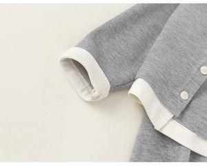 Macro detail of soft grey knit fabric with white ribbed cuffs and tiny button accents