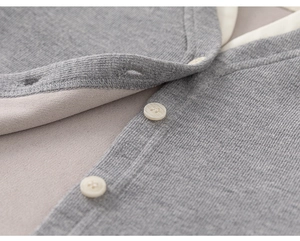 Detailed macro view of grey knit cardigan fabric with beige buttons and fine stitching