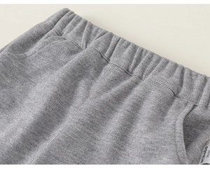 Detail shot of grey knitted trousers with elastic waistband and branded woven label