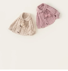 Close-up of knit cardigans with floral embroidery, scalloped collars and pom-poms