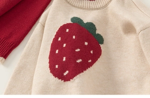 Detailed view of kids beige knitted sweater with vibrant strawberry motif and soft texture