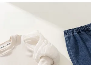 Détail du haut en tricot pour filles avec manches bouffantes et jean bleu marine