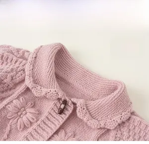 Close-up of pink knit cardigan featuring floral texture and classic horn button detail