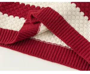Close-up of the red and white striped knit texture and elastic ribbed hem of the sweater