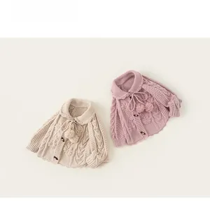 Detail of knit cardigans with floral embroidery, pom-poms, and wooden toggle buttons